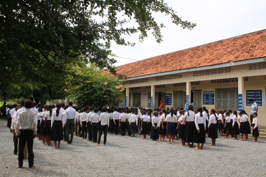 Students gather for a school assembly outside in Cambodia, fostering a sense of community.