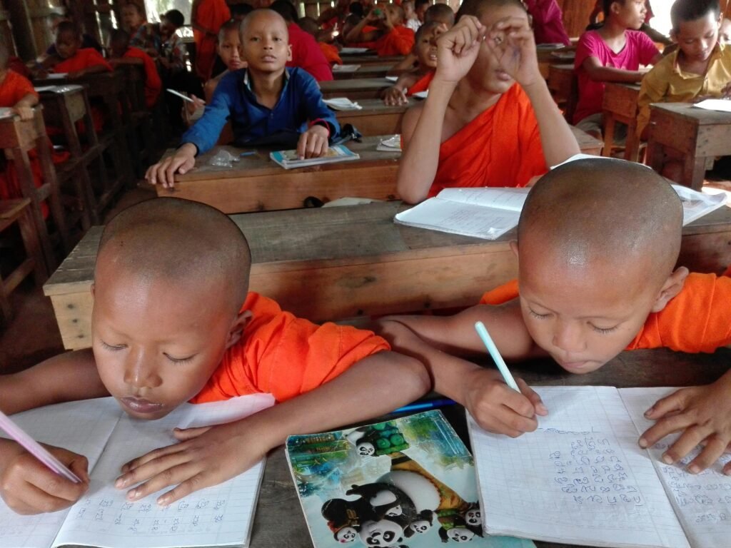 Young monks in Cambodia focus on writing in a classroom setting.